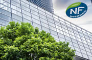 Un arbre devant un immeuble avec le logo NF environnement en haut à gauche du visuel
