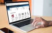 Une main qui utilise un ordinateur ouvert avec le site internet de Sonepar sur l'écran
